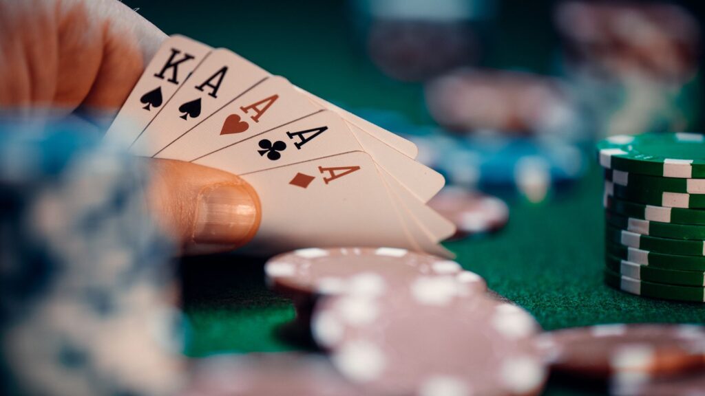 Main de poker avec des as et des jetons sur un tapis vert